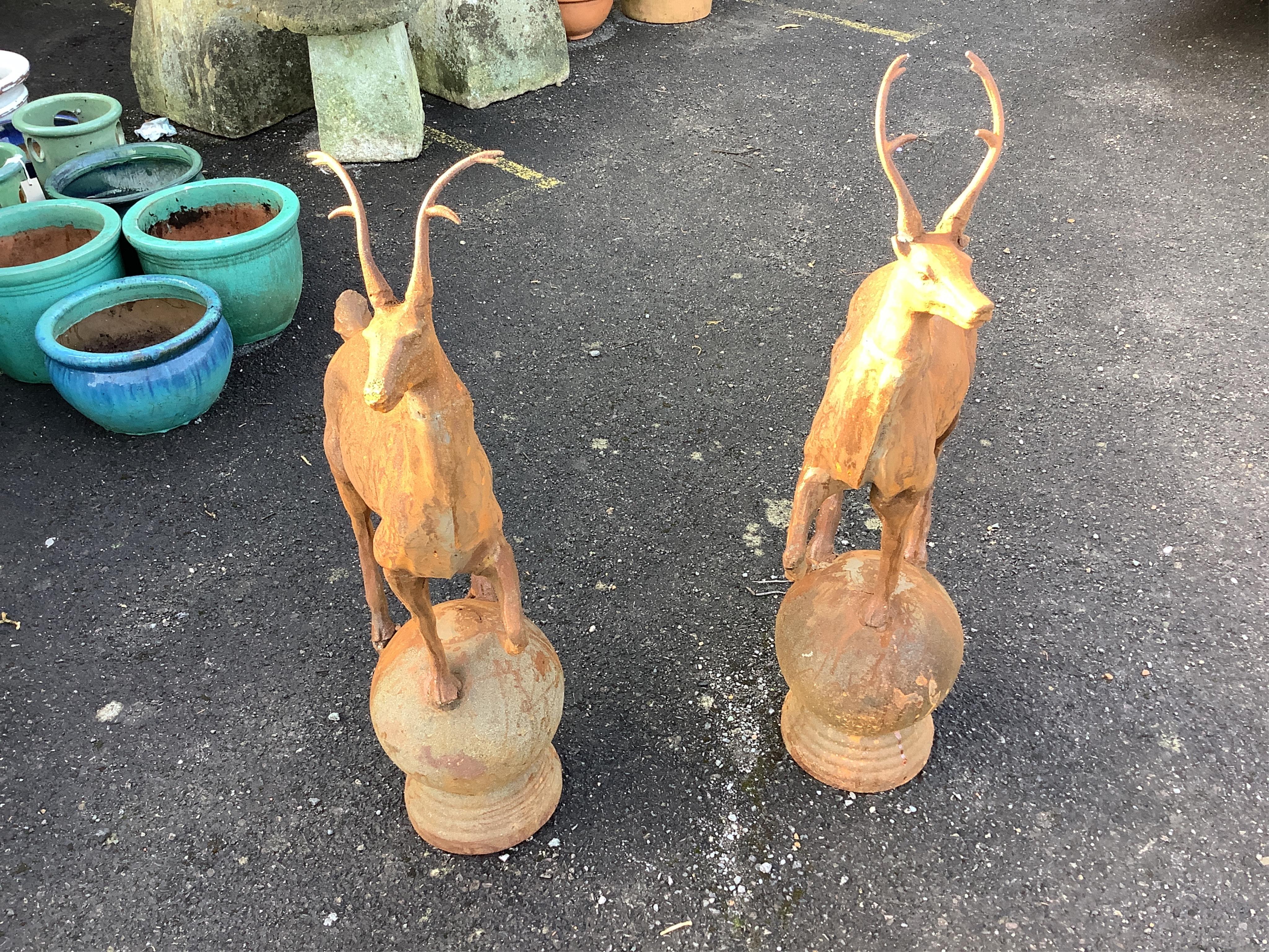 A pair of cast iron finials as deer standing upon spheres, height 92cm. Condition - weathered